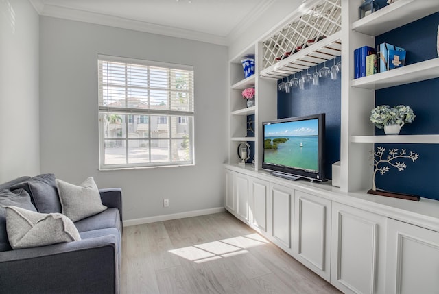 living room featuring built in shelves, light hardwood / wood-style floors, and crown molding