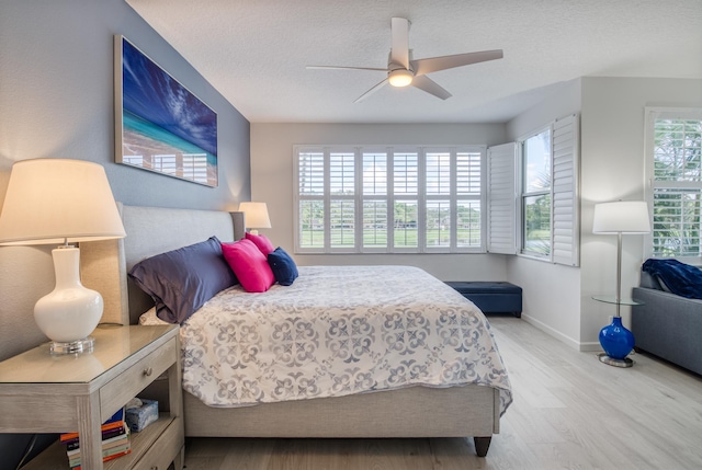 bedroom with multiple windows, a textured ceiling, light wood-type flooring, and ceiling fan