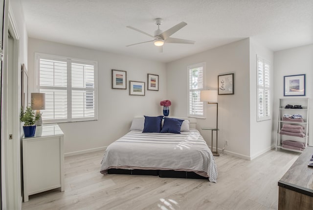 bedroom featuring a textured ceiling, light wood-type flooring, and ceiling fan