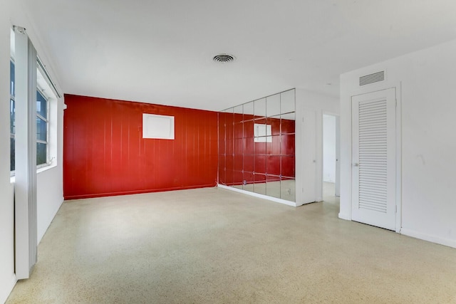 spare room with speckled floor, visible vents, and baseboards