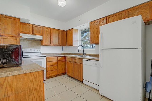 kitchen featuring light tile patterned flooring, under cabinet range hood, white appliances, a sink, and brown cabinetry