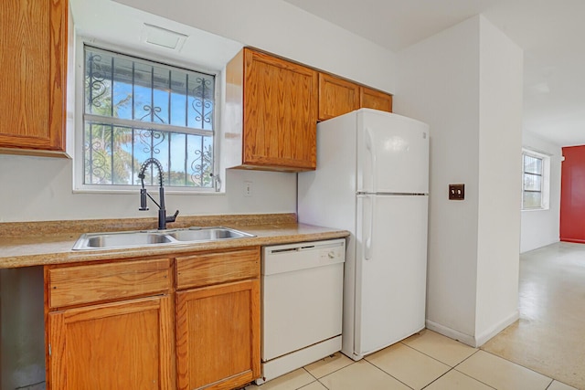 kitchen with white appliances, light countertops, a sink, and brown cabinetry