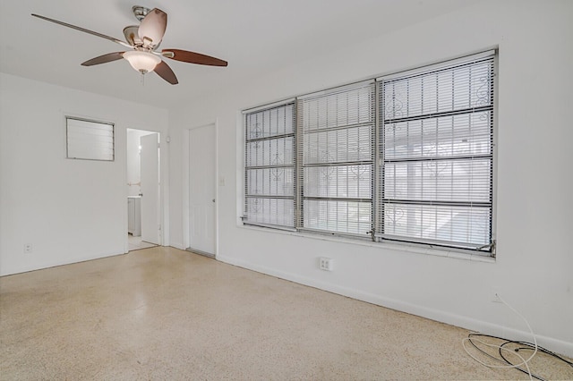 spare room featuring light speckled floor, ceiling fan, and baseboards