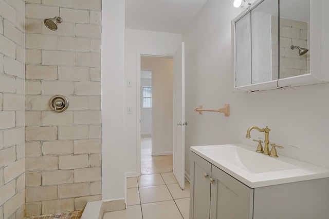 bathroom with tile patterned floors, a tile shower, and vanity