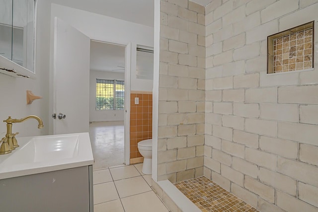 full bathroom with toilet, tile walls, vanity, a tile shower, and tile patterned floors