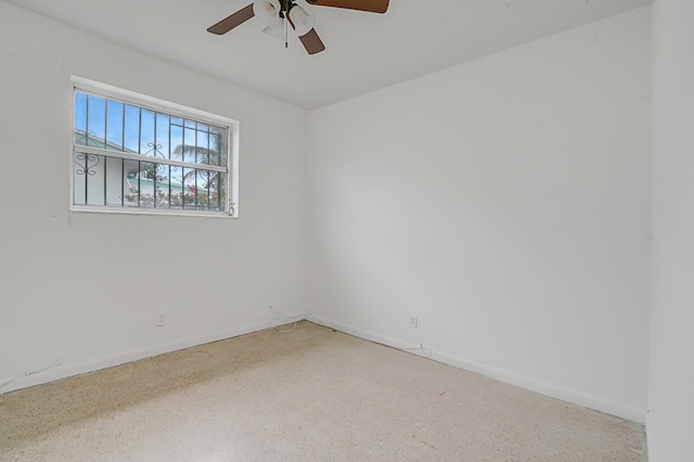 empty room with ceiling fan, baseboards, and speckled floor