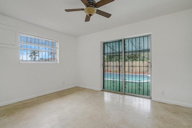 unfurnished room featuring speckled floor, a ceiling fan, and baseboards