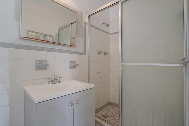 full bathroom featuring a shower stall, tile walls, and vanity