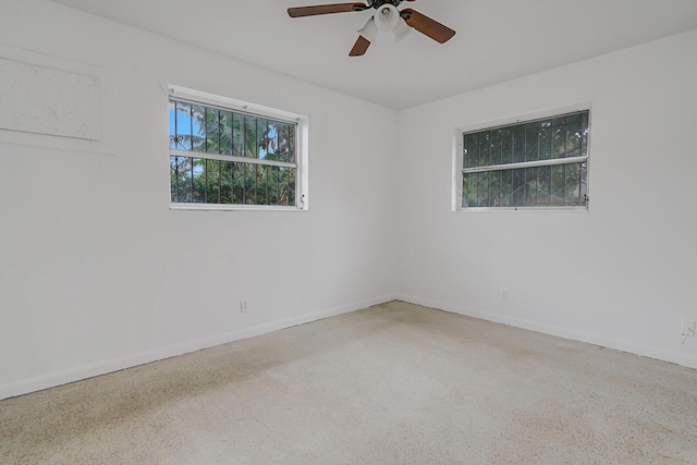 empty room with baseboards, a ceiling fan, and speckled floor