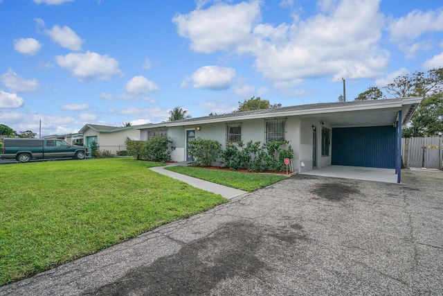 ranch-style home featuring aphalt driveway, fence, stucco siding, a carport, and a front yard