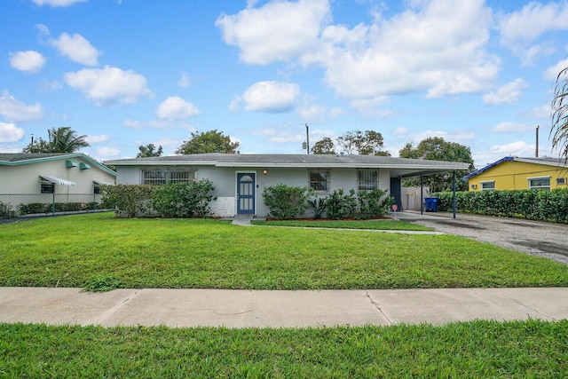 single story home featuring an attached carport, fence, driveway, stucco siding, and a front yard