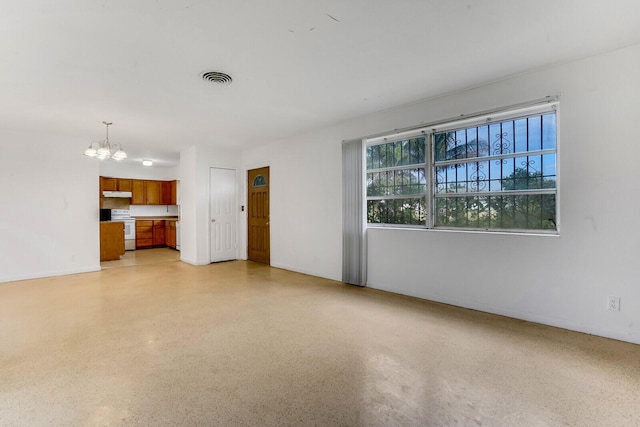 unfurnished living room with light speckled floor, visible vents, a notable chandelier, and baseboards