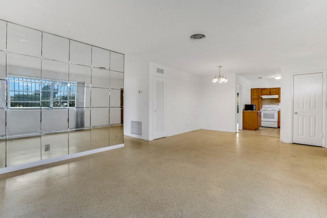 unfurnished room featuring visible vents, an inviting chandelier, and speckled floor