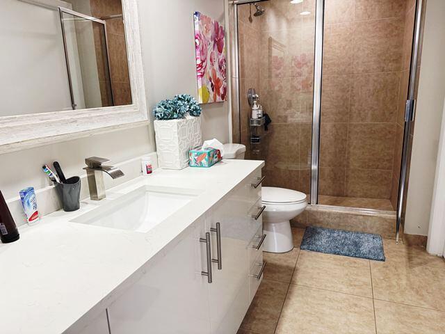 bathroom featuring toilet, vanity, tile patterned floors, and walk in shower