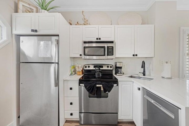 kitchen with sink, white cabinets, ornamental molding, decorative backsplash, and appliances with stainless steel finishes