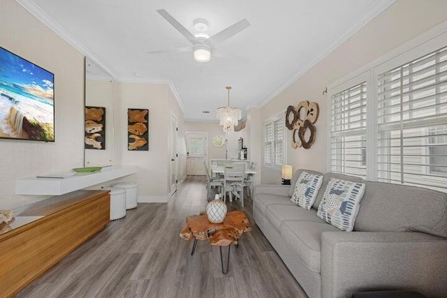 living room featuring ceiling fan with notable chandelier, ornamental molding, and wood-type flooring