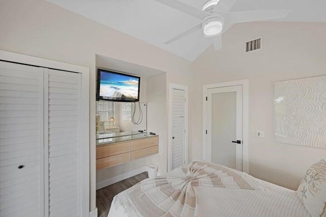 bedroom with hardwood / wood-style flooring, two closets, ceiling fan, and vaulted ceiling