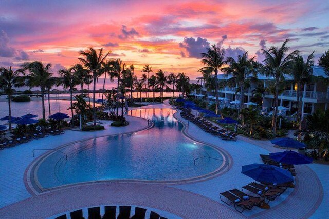 pool at dusk with a patio and a water view