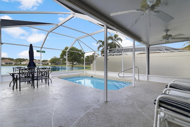 view of pool with glass enclosure, ceiling fan, a water view, and a patio