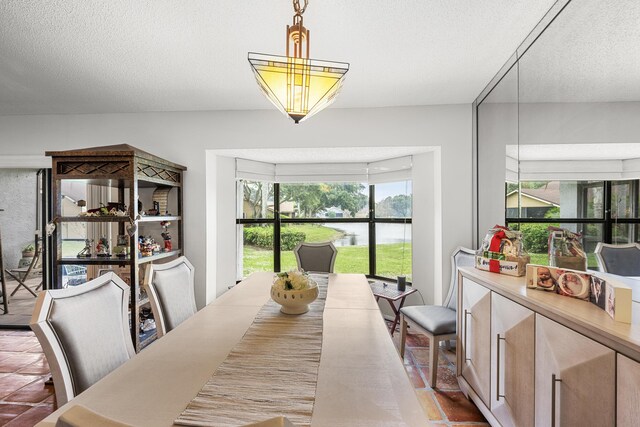 dining room with a water view and a textured ceiling