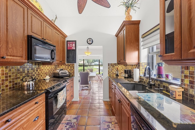 kitchen with sink, ceiling fan, dark stone counters, and black appliances