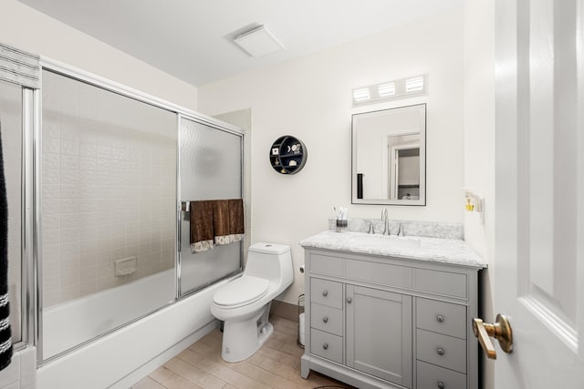 full bathroom featuring vanity, bath / shower combo with glass door, and toilet