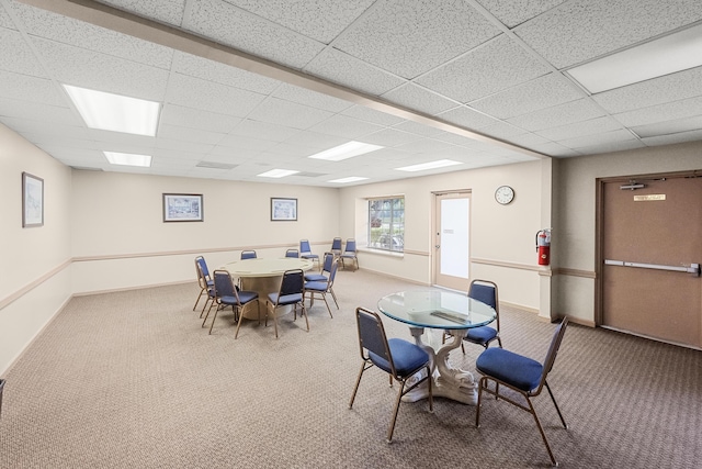 carpeted dining space with a drop ceiling