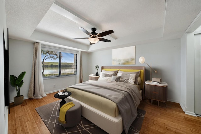 bedroom featuring a raised ceiling, ceiling fan, and wood-type flooring