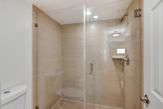 bathroom featuring tile patterned flooring, an enclosed shower, and toilet