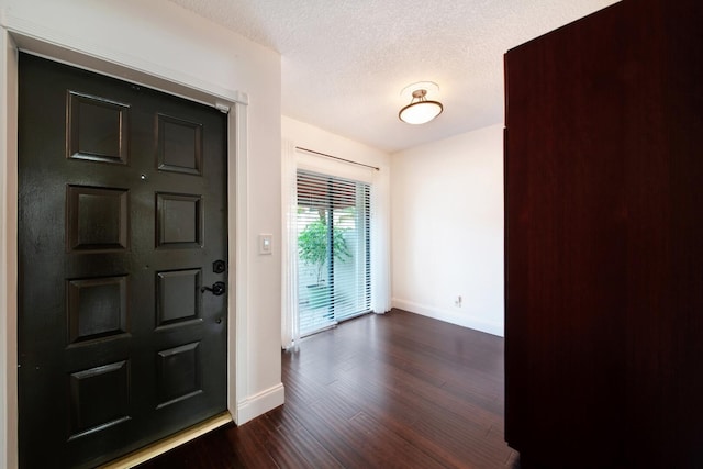 entryway with dark wood-type flooring and a textured ceiling