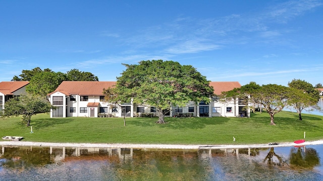 back of house with a water view and a lawn