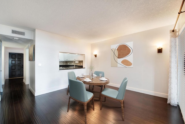 dining space with a textured ceiling and dark wood-type flooring