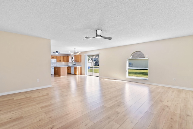 unfurnished living room with ceiling fan with notable chandelier, sink, a textured ceiling, and light hardwood / wood-style flooring