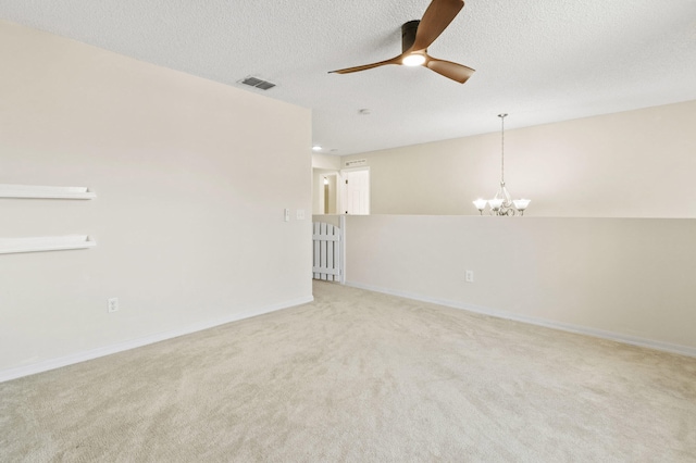 carpeted empty room featuring a textured ceiling and ceiling fan with notable chandelier