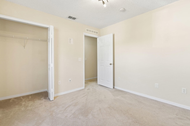 unfurnished bedroom with light carpet, a closet, and a textured ceiling