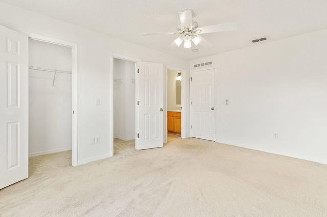 unfurnished bedroom with ceiling fan, light colored carpet, and a walk in closet