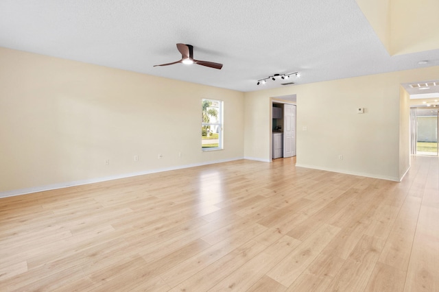 spare room with washer and dryer, a textured ceiling, light wood-type flooring, and ceiling fan