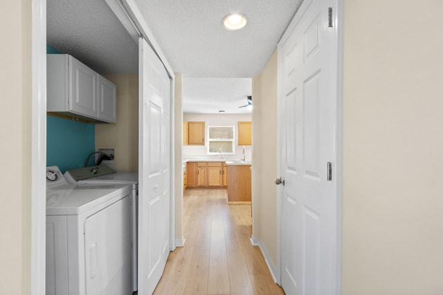 clothes washing area featuring cabinets, light hardwood / wood-style flooring, ceiling fan, separate washer and dryer, and a textured ceiling