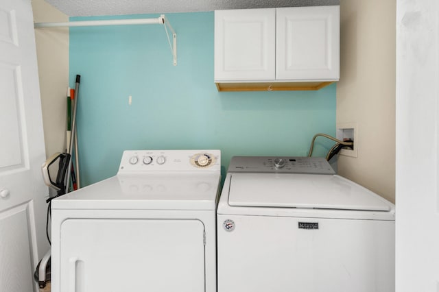 clothes washing area featuring cabinets, a textured ceiling, and washing machine and clothes dryer