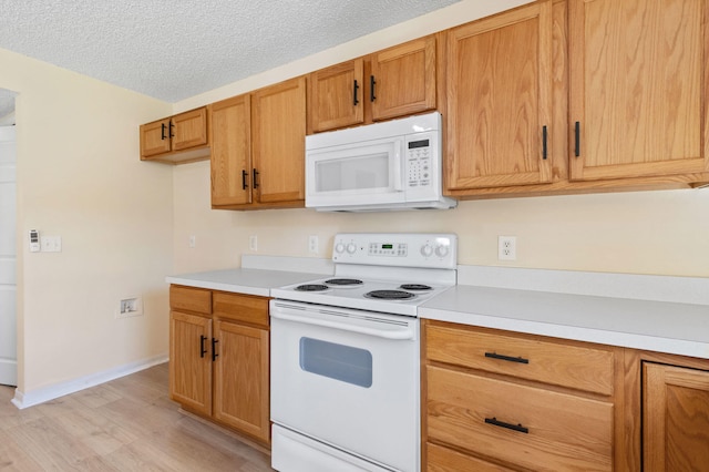 kitchen featuring light wood-type flooring, a textured ceiling, and white appliances