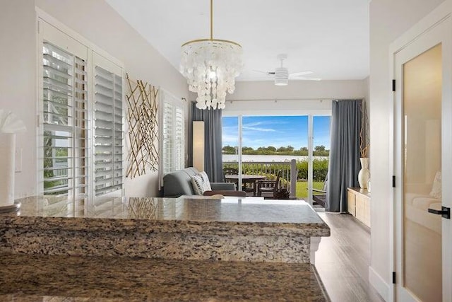 dining space featuring ceiling fan with notable chandelier and wood-type flooring