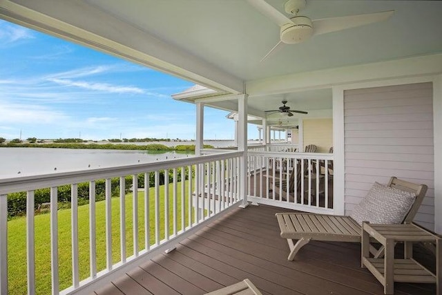 wooden terrace featuring ceiling fan and a lawn