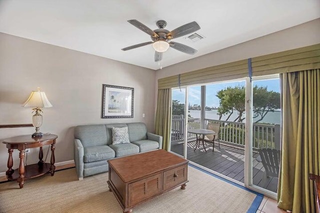 living room featuring ceiling fan and a water view