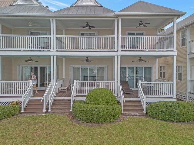 back of house featuring a porch, a balcony, ceiling fan, and a lawn