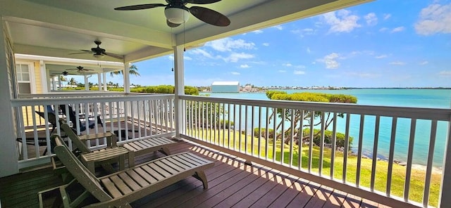 wooden terrace featuring ceiling fan, a view of the beach, and a water view