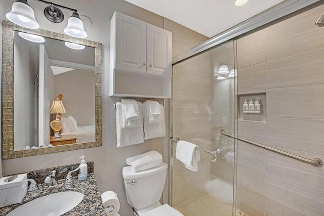 bathroom with toilet, vanity, and a shower with shower door