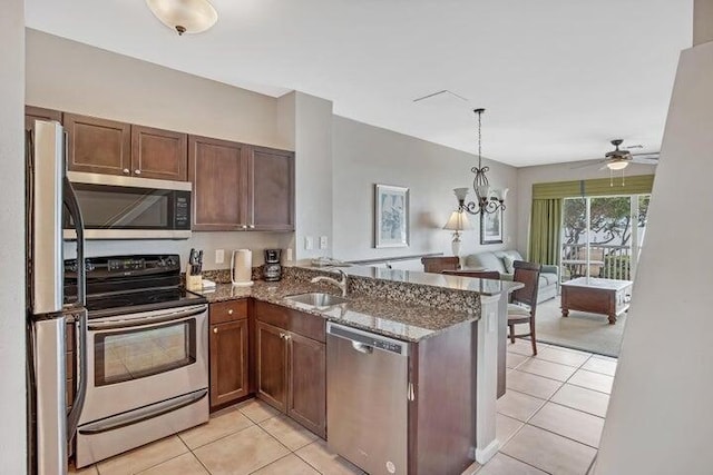 kitchen featuring stainless steel appliances, sink, light tile patterned floors, kitchen peninsula, and dark stone counters