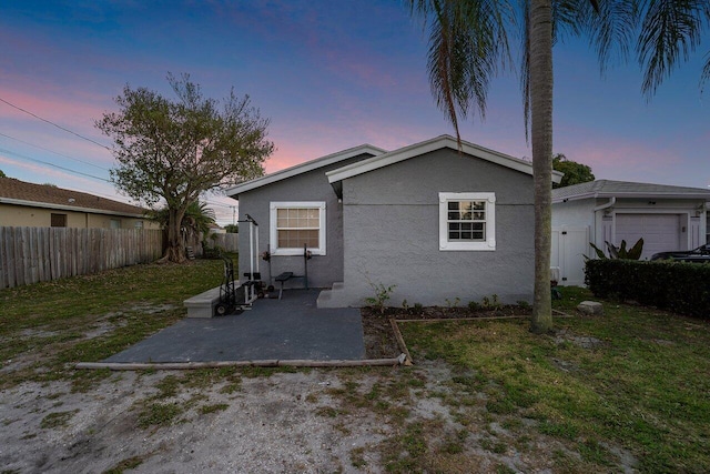 back house at dusk featuring a yard and a patio