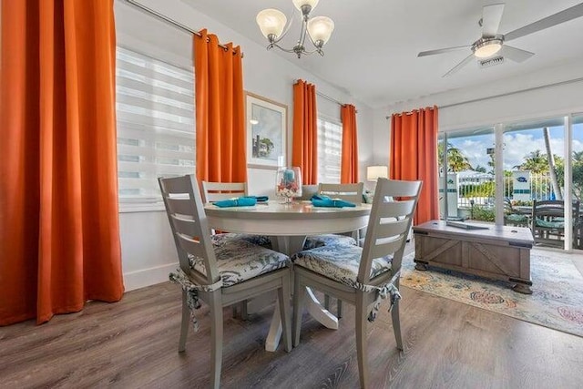 dining area featuring wood-type flooring and ceiling fan with notable chandelier