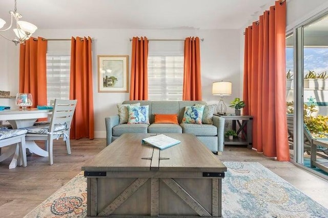 living room with light hardwood / wood-style floors, a notable chandelier, and a healthy amount of sunlight